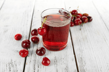 Glass of fresh juice with cherries on wooden table close up