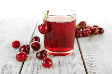 Glass of fresh juice with cherries on wooden table close up