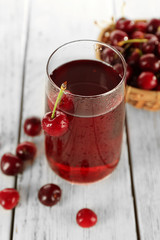 Glass of fresh juice with cherries on wooden table close up
