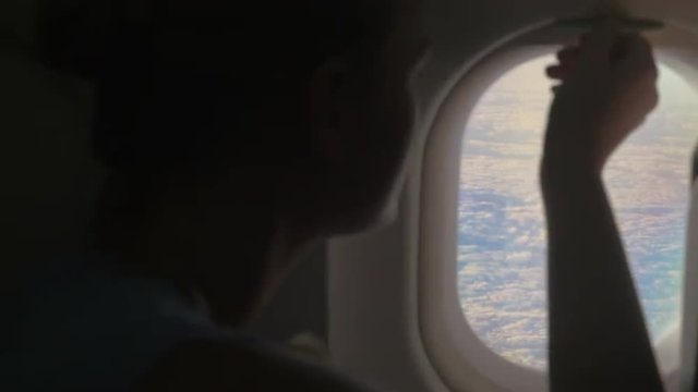 Woman looking out illuminator in plane