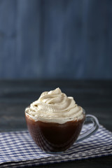 Cup of coffee with cream on color wooden background