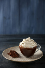 Cup of coffee with cream on color wooden background