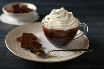 Cup of coffee with cream on color wooden background