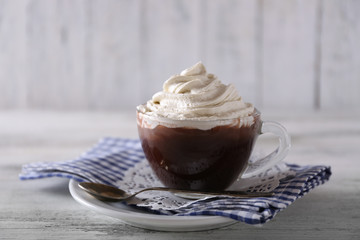 Cup of coffee with cream on color wooden background