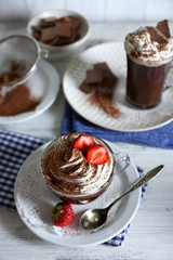 Cups of coffee with cream and fresh strawberry on color wooden background