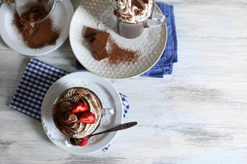 Cups of coffee with cream and fresh strawberry on color wooden background