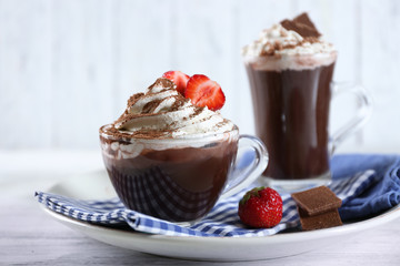 Cups of coffee with cream and fresh strawberry on color wooden background