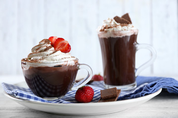 Cups of coffee with cream and fresh strawberry on color wooden background
