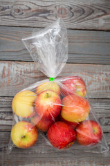 Apple fruit in plastic bag on wood table