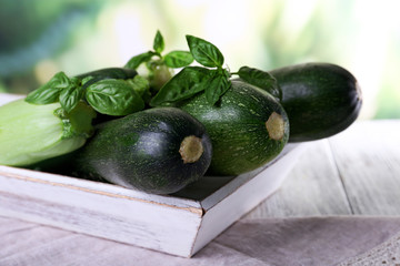 Fresh zucchini with squash and basil on bright background