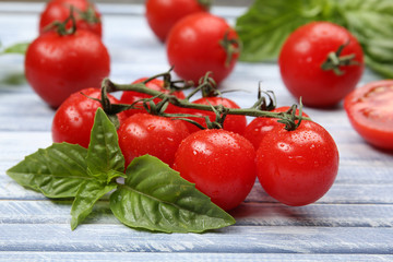 Fresh tomatoes with basil on wooden table close up