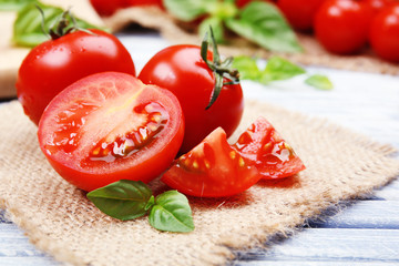Fresh tomatoes with basil on wooden table close up