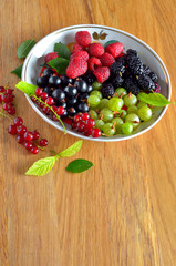 Assorted fresh garden berries on a  wooden background, space for text, close-up