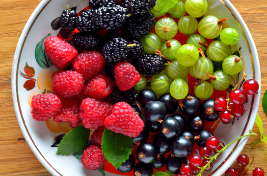 dish of fresh seasonal berries on wooden table, close-up, top view
