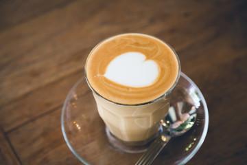 Cup of coffee with heart pattern  on wood table ( Filtered image