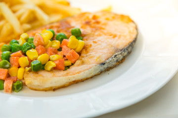 Grilled salmon steak meal served with salad and French fries