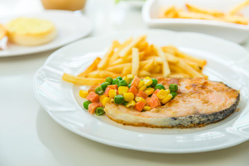 Grilled salmon steak meal served with salad and French fries