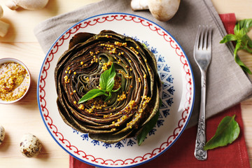 Boiled artichokes on plate, on color wooden background