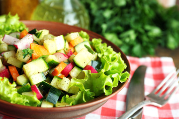 Wooden bowl of fresh vegetable salad on napkin, closeup