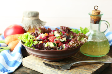 Wooden bowl of fresh vegetable salad on table, closeup