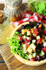 Wooden bowl of fresh vegetable salad on table, closeup