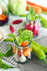 Fresh vegetables in glass bottles on table, closeup