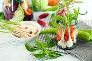 Fresh vegetables in glass bottles on table, closeup