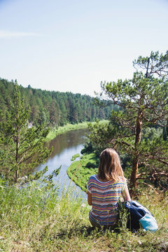 Young woman backpaking. River viewed from a top of the hill