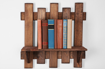 Wooden shelf with books on wall background