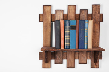 Wooden shelf with books on wall, closeup