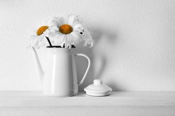 Decorative teapot with flowers on wooden shelf  on white wallpaper background