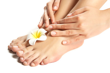 Female feet at spa pedicure procedure with plumeria isolated on white