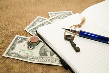 Opened notebook, pen, key and money on the old tissue