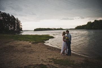 Newly-married couple embraces against lake 3273.