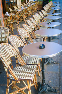 Empty tables between dining hours along Paris cobblestone alley way