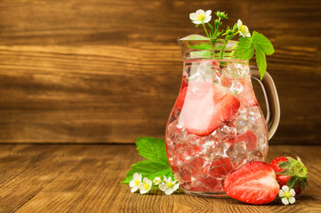 refreshing drink with a strawberry and ice in a glass jug
