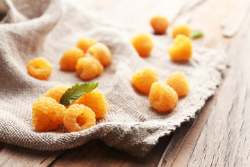 Yellow raspberries on sackcloth on wooden table, closeup