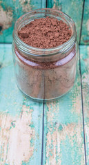 Fototapeta na wymiar Brown pure cocoa powder in a mason jar over rustic wooden background