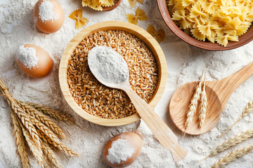 Preparing pasta with white flour and wheat on table, closeup