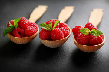 Fresh red raspberries in spoons on wooden table, closeup