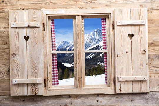 Wooden window with snowy mountain reflections
