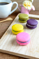 Colorful macaroons and a cup of coffee on wooden table
