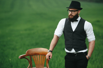 man with a beard, thinking in the field near chair