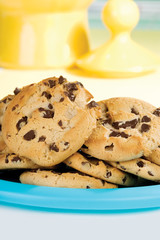 Plate of Chocolate Chip Cookies – A stack of chocolate chip cookies. Yellow cookie jar in background.