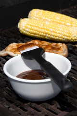 Summer Grilling – Corn on the cob and chicken on the grill, with barbecue sauce in the foreground.