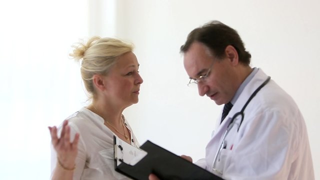 Doctor giving good news to a blonde female patient showing results on papers on clipboard