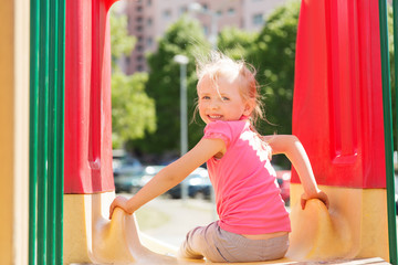 happy little girl on slide at children playground