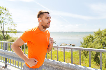 happy man with earphones running outdoors