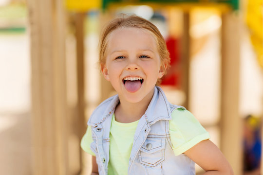 happy little girl showing tongue on playground