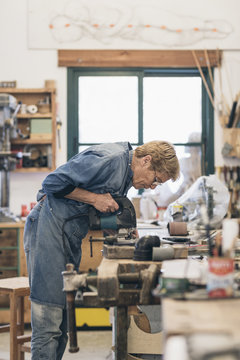 Woman senior artist cutting wood in a workshop